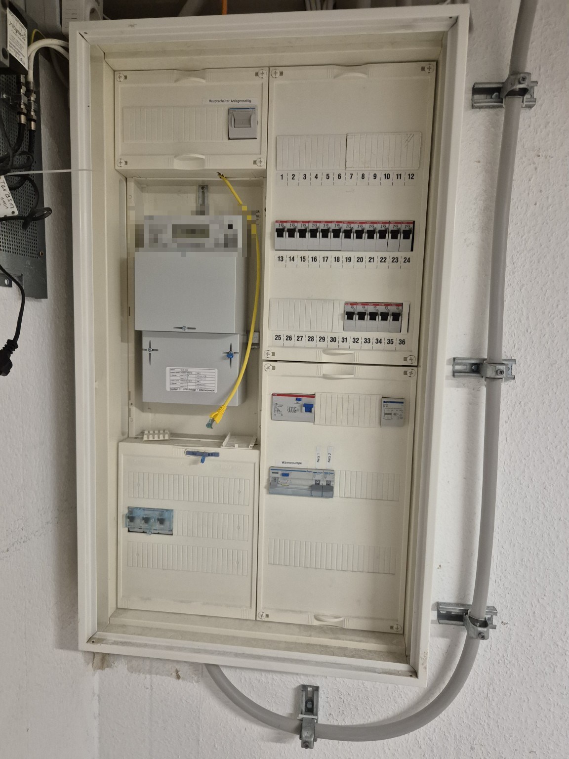 Umgebauter Zählerschrank mit Hauptschalter oberhalb des Zählers, neuer Hauptleitung und vorbereiteter gelber Steuerleitung, Projekt Dortmund (Zähleranzeige unkenntlich gemacht)